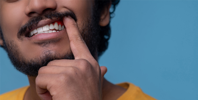 Man smiling with finger on chin in thoughtful pose against blue background