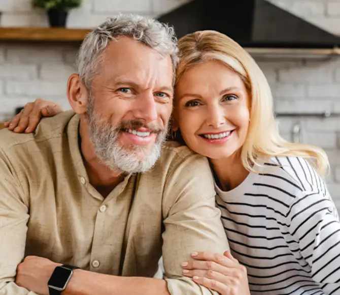 Smiling mature couple embracing in modern kitchen, promoting dental care and wellness.