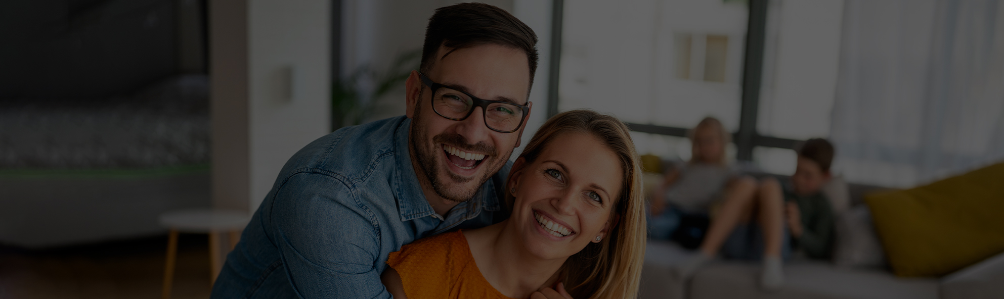 Smiling couple embracing indoors, dental office setting with blurred background