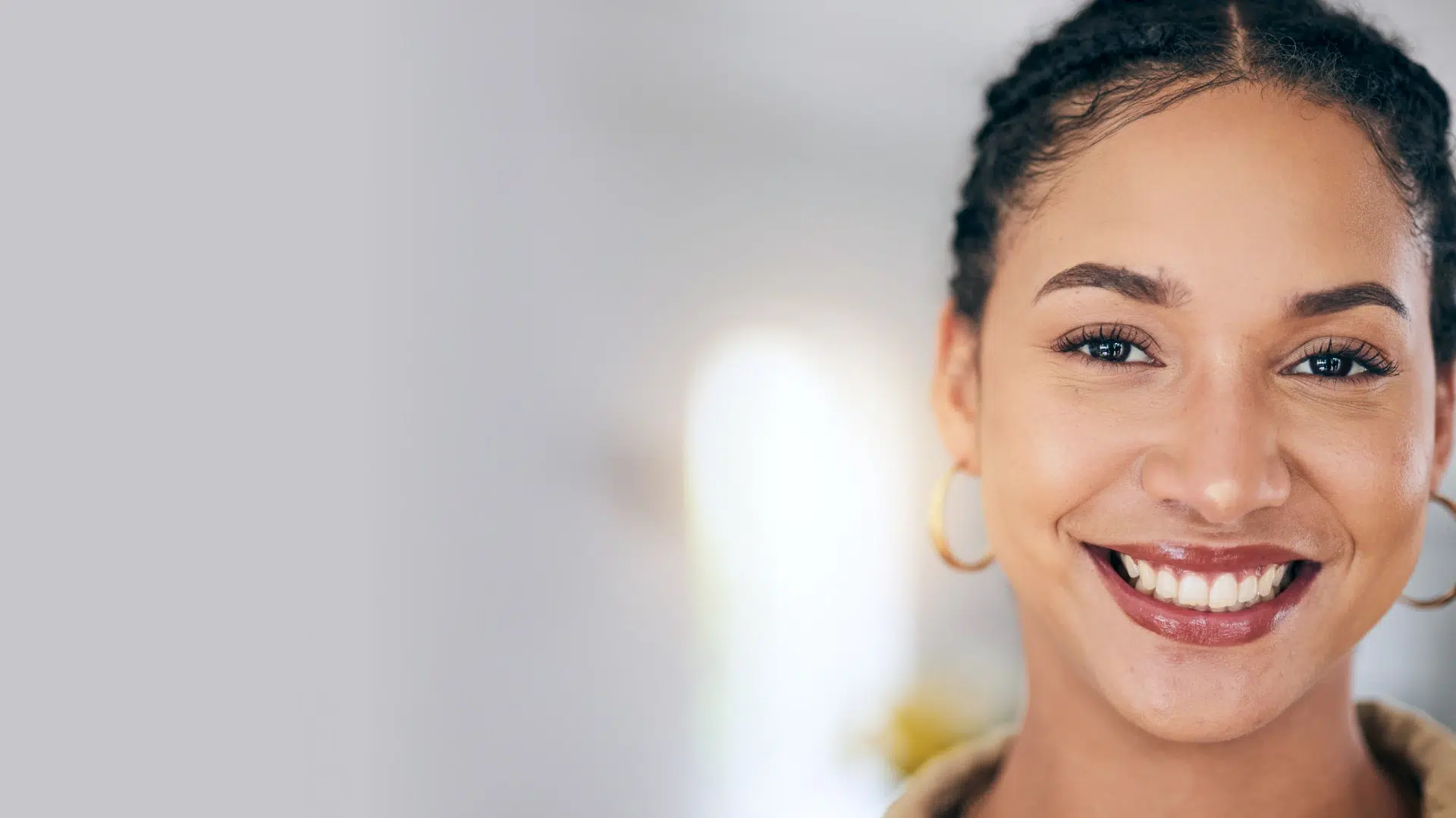Young woman smiling brightly at camera in dental office setting, displaying healthy teeth.